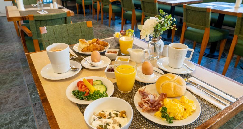 a table with plates of food and cups of orange juice at PLAZA INN Regensburg in Regensburg