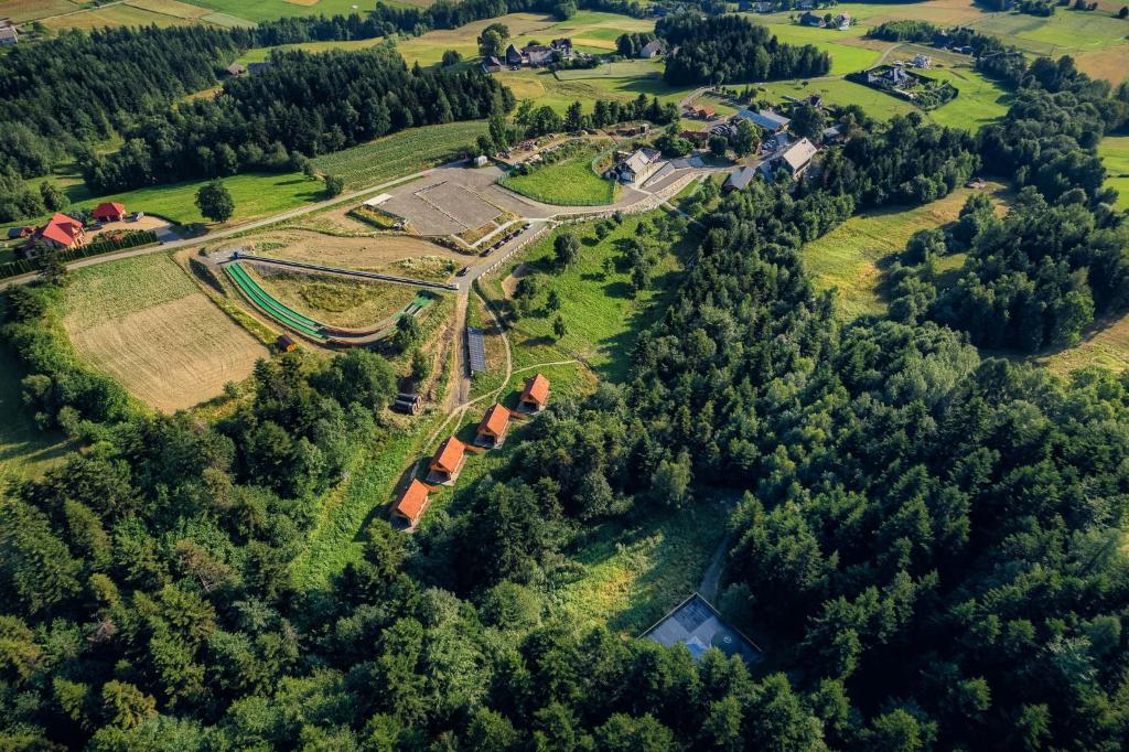 Aerial view of rural landscape with clustered small cabins, green fields and surrounding forest.