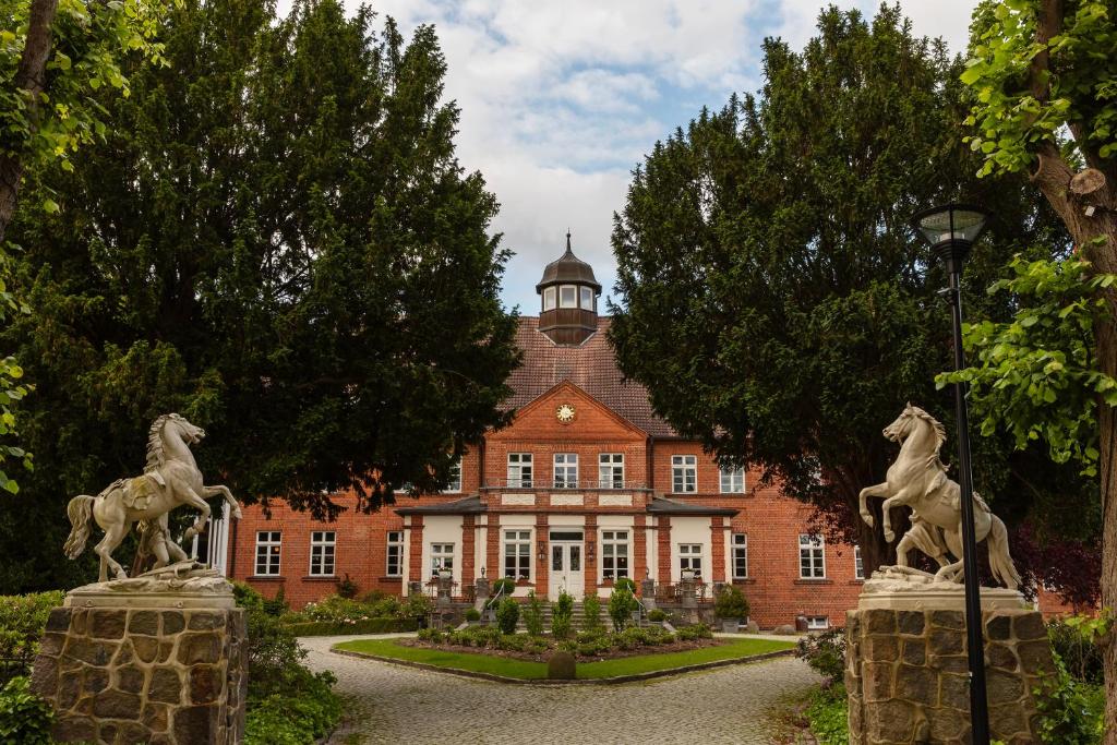 ein Gebäude mit zwei Pferdestatuen davor in der Unterkunft Schloss Basthorst in Crivitz