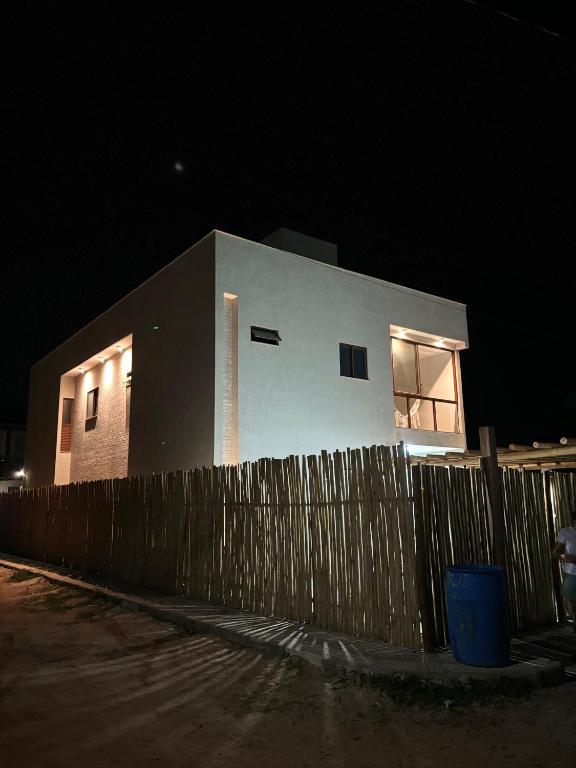 a building with a fence in front of it at night at Pousada Solare Home in São Miguel do Gostoso