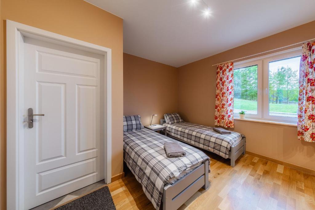 Bright twin bedroom seen from doorway, two single beds with plaid covers and window.
