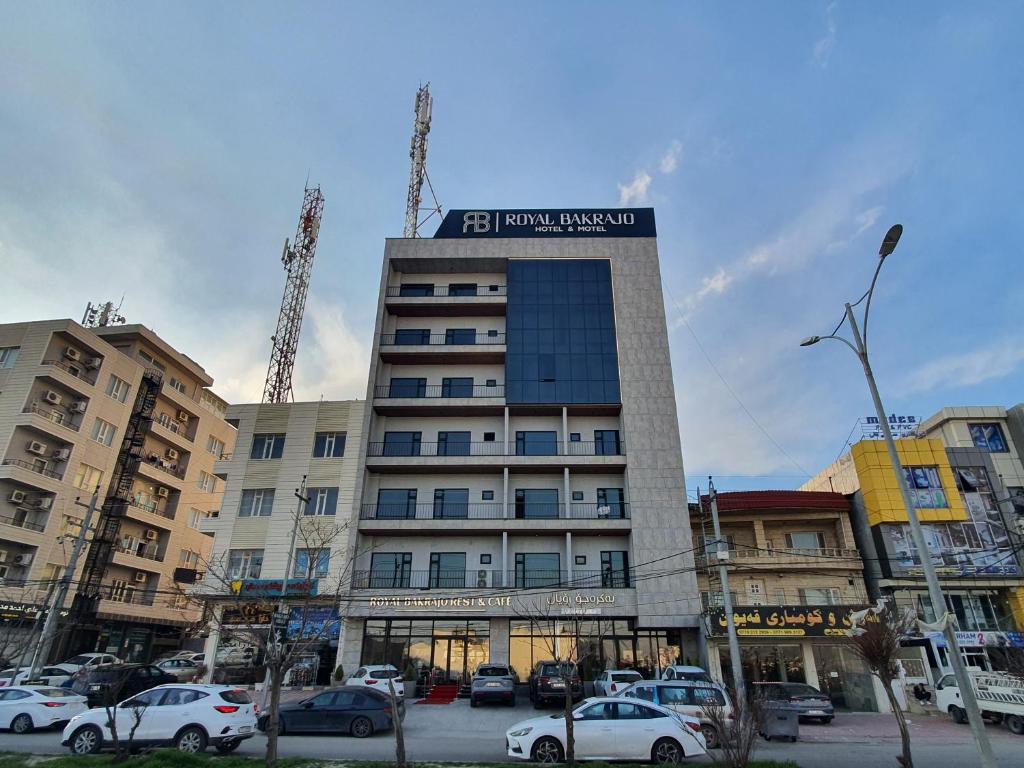 een hoog gebouw met auto's ervoor geparkeerd bij Royal Bakrajo Hotel in As Sulaymānīyah
