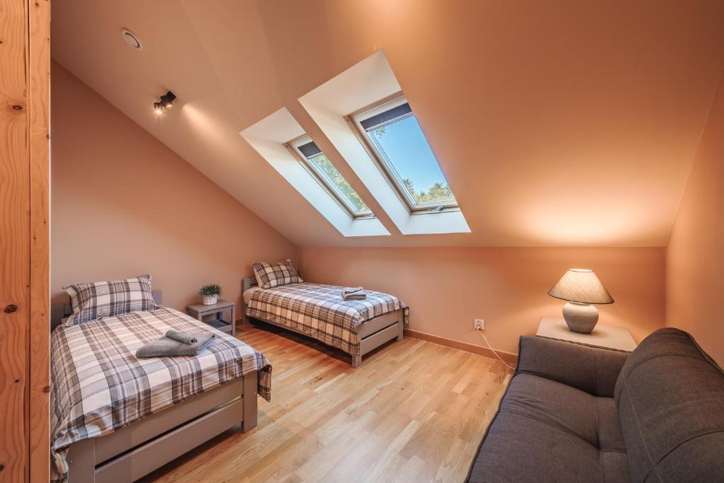 Cozy attic bedroom with two single beds under skylights, side lamp and small sofa.