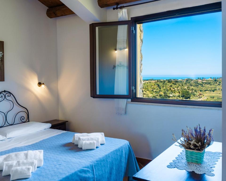 a room with a bed and a large window at Casale Ginisara in Castellammare del Golfo