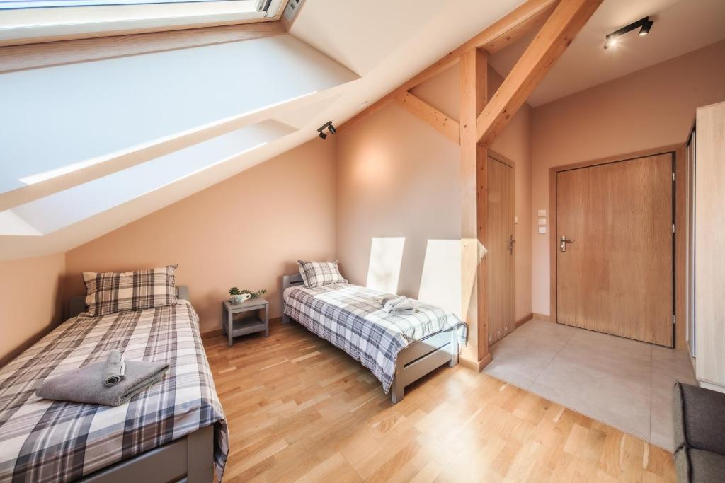 Attic twin bedroom with skylight windows, two beds, exposed wooden beam and bedside table.