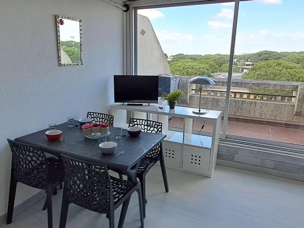 d'une table à manger avec des chaises et d'un bureau avec une fenêtre. dans l'établissement Studio cabine climatisé, piscine, parking, animaux admis, 350m plage - FR-1-250-62, au Grau-du-Roi