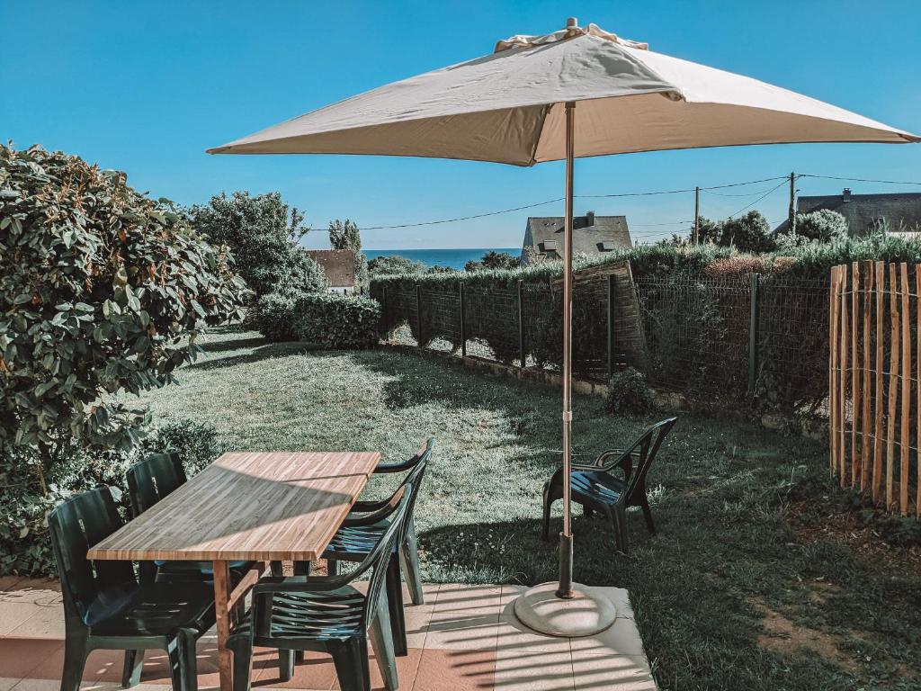 Una mesa y sillas con una sombrilla en un patio. en VVF Golfe du Morbihan Sarzeau Arzon, en Sarzeau
