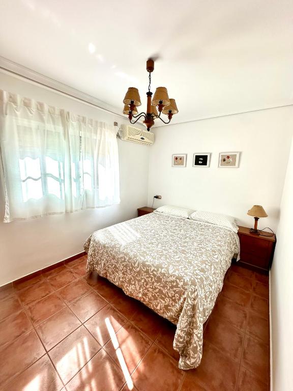 a bedroom with a bed and a chandelier at Apartamento a pie de playa en El Portil in El Portil