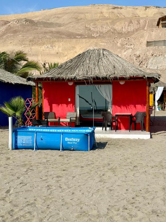 a red and blue building on the beach at Bungalows en playa Wakama in San Vicente de Cañete