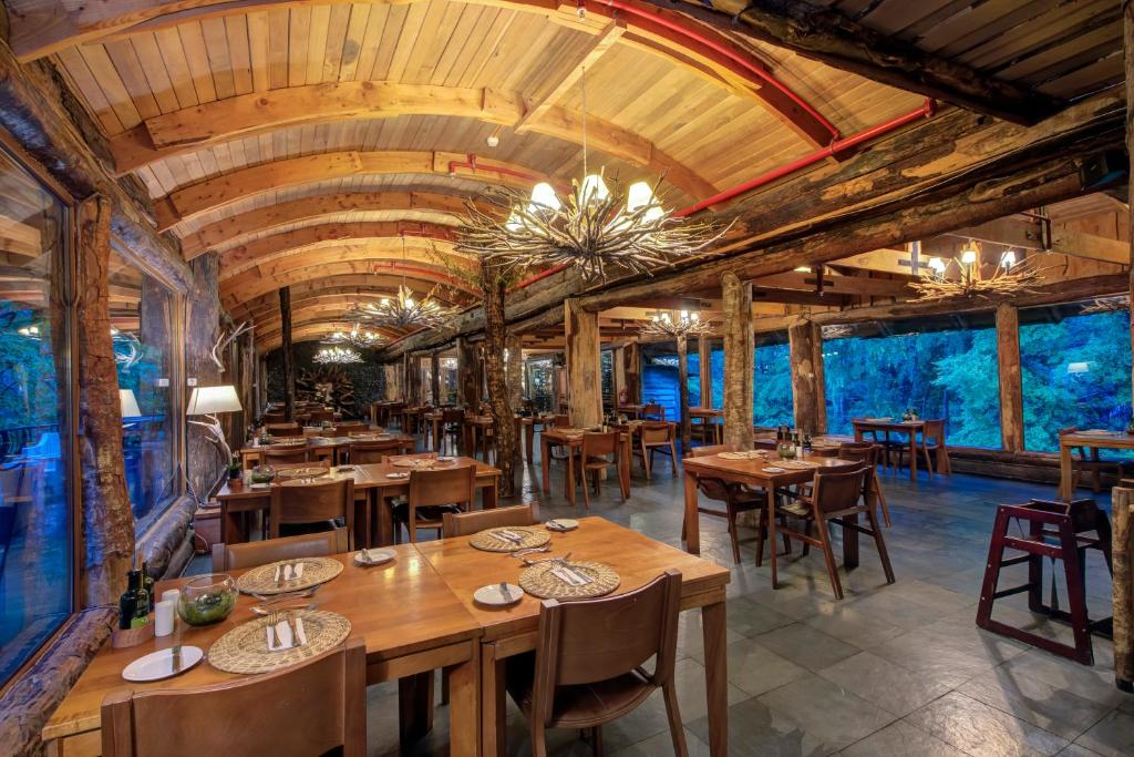 una sala da pranzo con tavoli e sedie in legno di Huilo Huilo Reino Fungi a Huilo Huilo