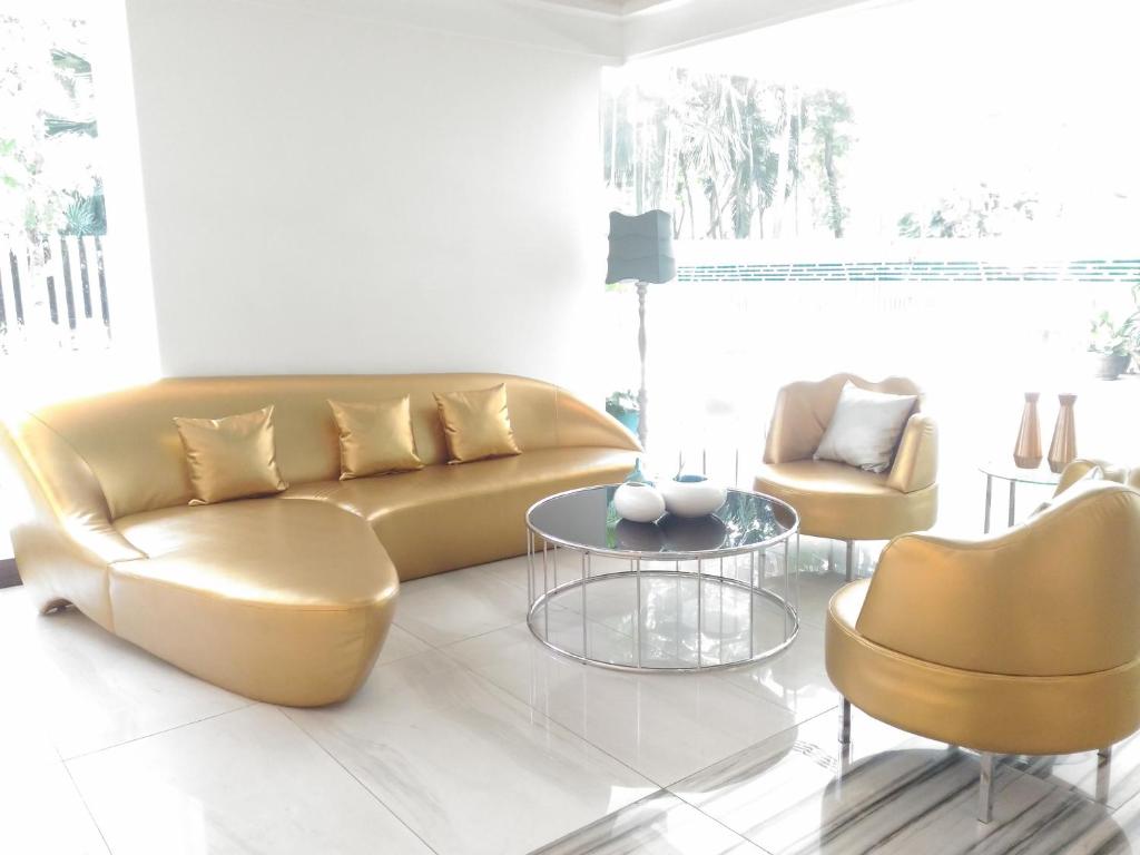 A bright sitting area with a curved sofa, armchairs and a glass coffee table.