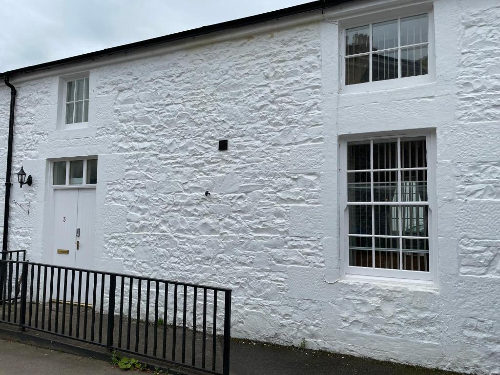 a white brick building with a white door and windows at 3 Telford Mews in Dumfries