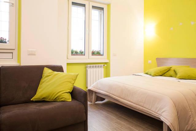 a bedroom with a bed and a couch and two windows at The Green Corner in Rome