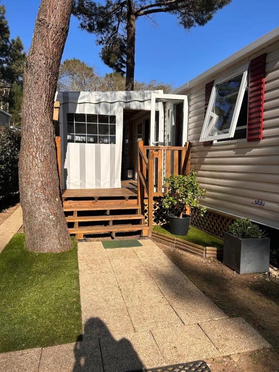 ein Haus mit einer Holztür und einem Baum in der Unterkunft Mobilhome Calme 6 Personnes Camping Pierre Couché in Saint-Brevin-les-Pins