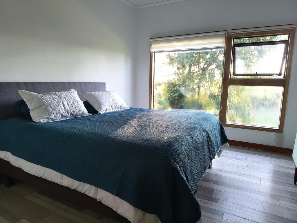a bedroom with a bed and a large window at Casa de Campo a 15 minutos de Villarrica in Catrico