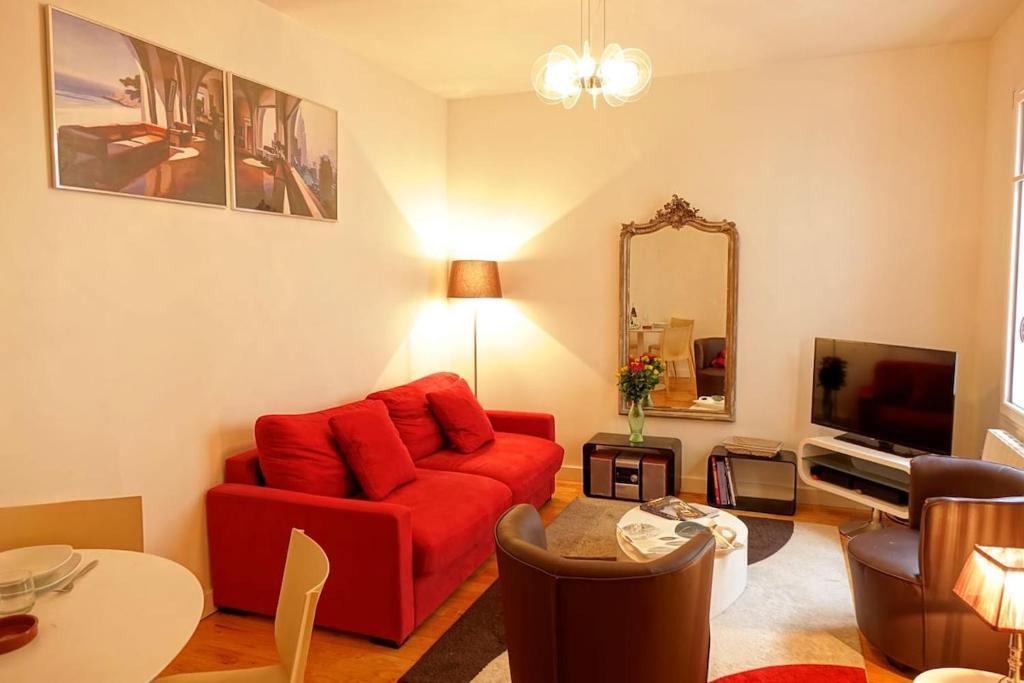 un salon avec un canapé rouge et un miroir dans l'établissement Biarritz 2 pièces en hypercentre, tout à pied, à Biarritz