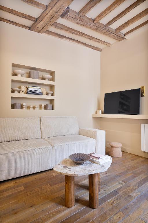 un salon avec un canapé blanc et une table dans l'établissement Appartement lumineux Marais 2 chambres, à Paris
