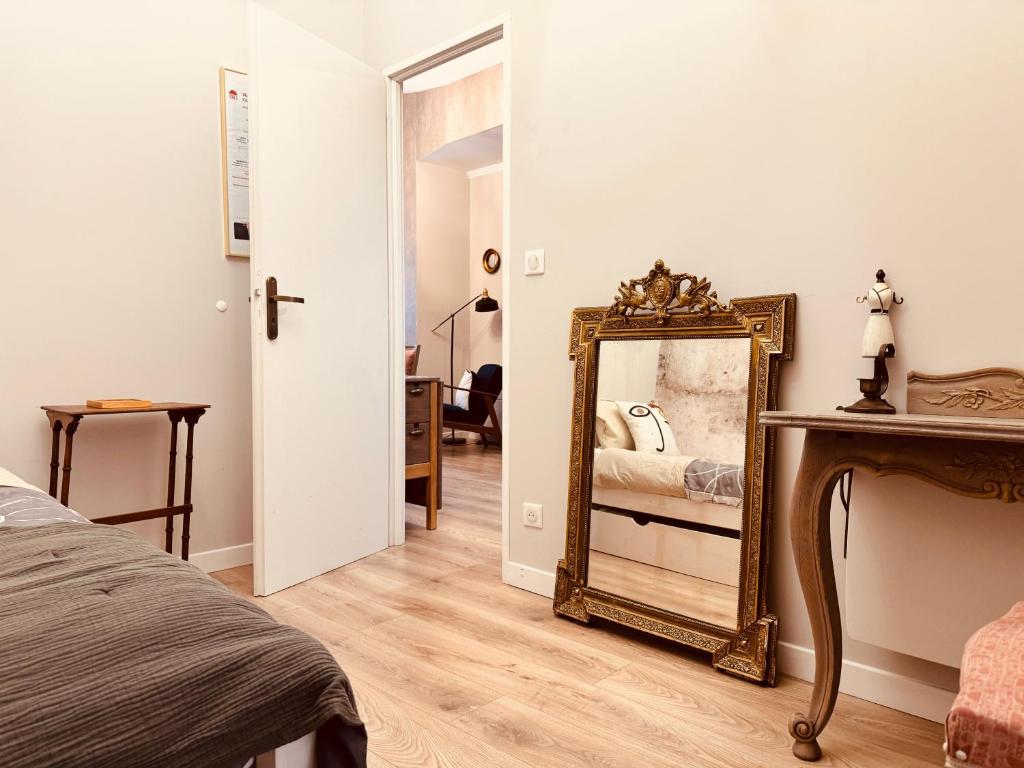 une chambre avec un miroir et un lit dans l'établissement Le Tailleur, centre historique, fibre, climatisation, ESS, rez-de-chaussée, BedinShop, à Romans-sur-Isère
