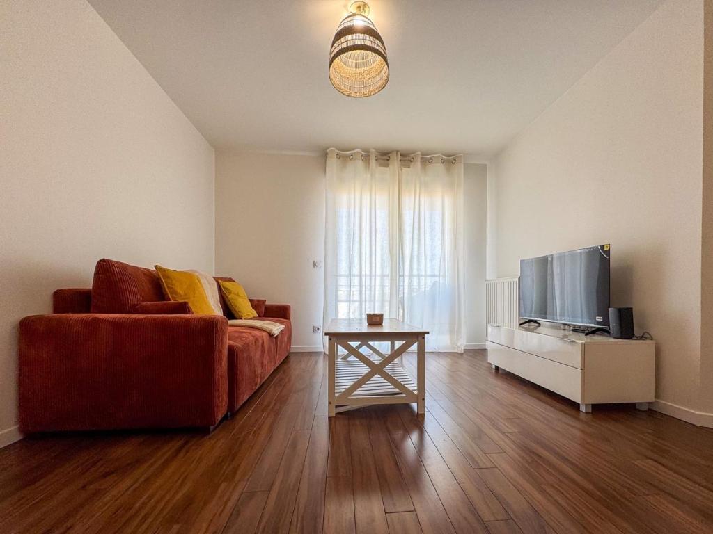 Una sala de estar con un sofá y un televisor. en House Novo Appt 10min de Paris Centre, en Aulnay-sous-Bois