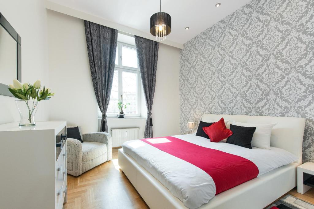 a white bedroom with a red and white bed and a chair at Neo Apartments in Krakow
