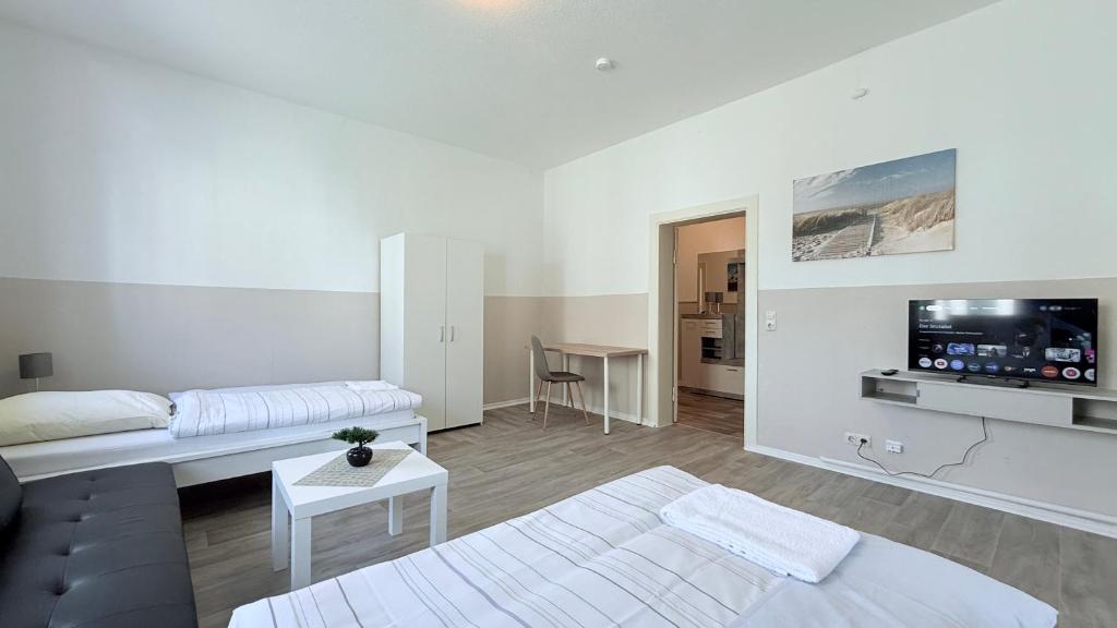 a white living room with a couch and a tv at Komfortable Apartments Neumünster Zentrum perfekt für Beruf & Handwerk in Neumünster
