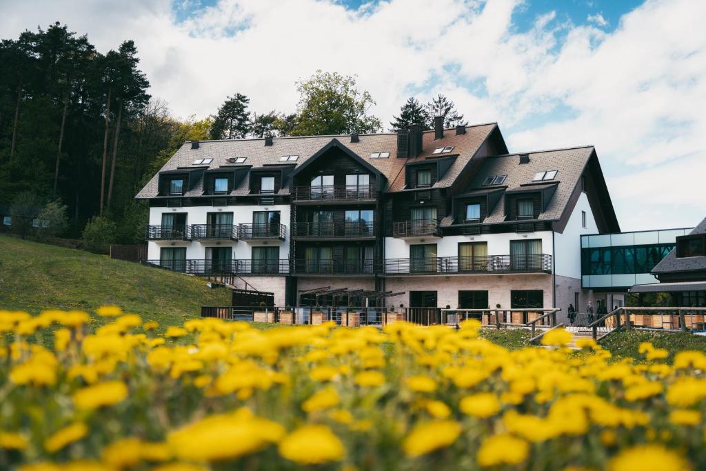 un grande edificio su una collina con fiori gialli di Hotel Arena Maribor a Maribor
