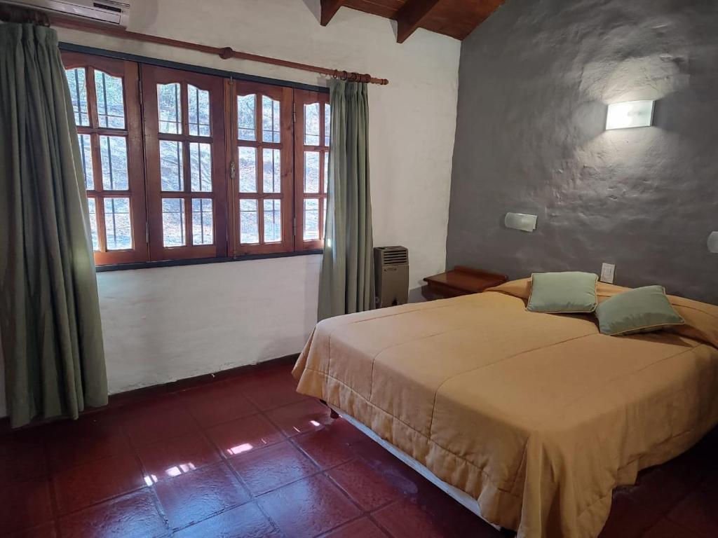 a bedroom with a bed in a room with windows at Green House in Villa General Belgrano