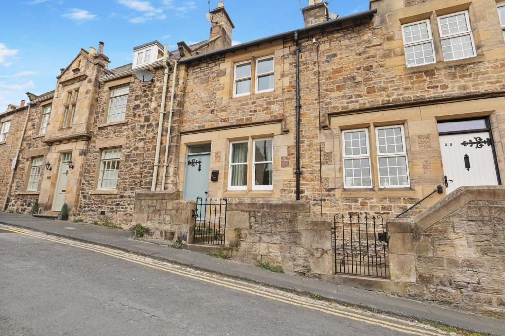 ein altes Backsteingebäude an der Straßenseite in der Unterkunft Daisy Cottage - North East Escapes in Corbridge