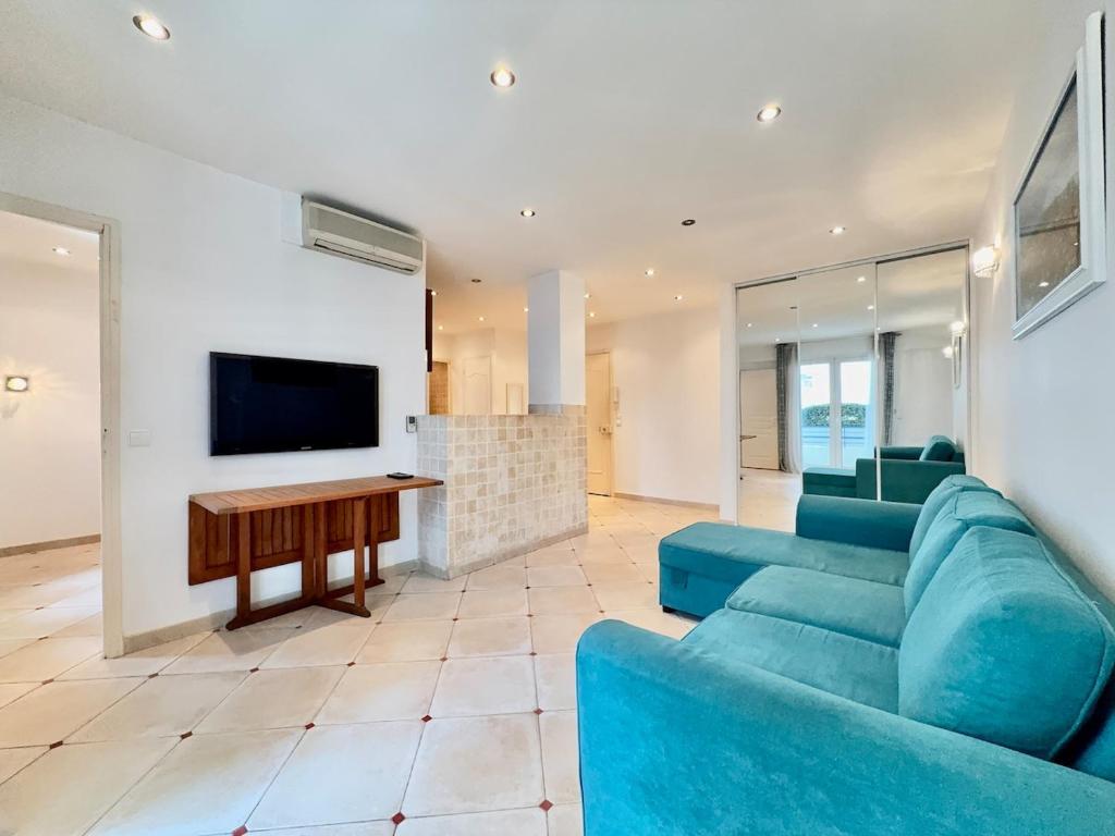 un salon avec un canapé bleu et une télévision à écran plat dans l'établissement Hypercentre - Vue Mer - Plage 50m, à Antibes