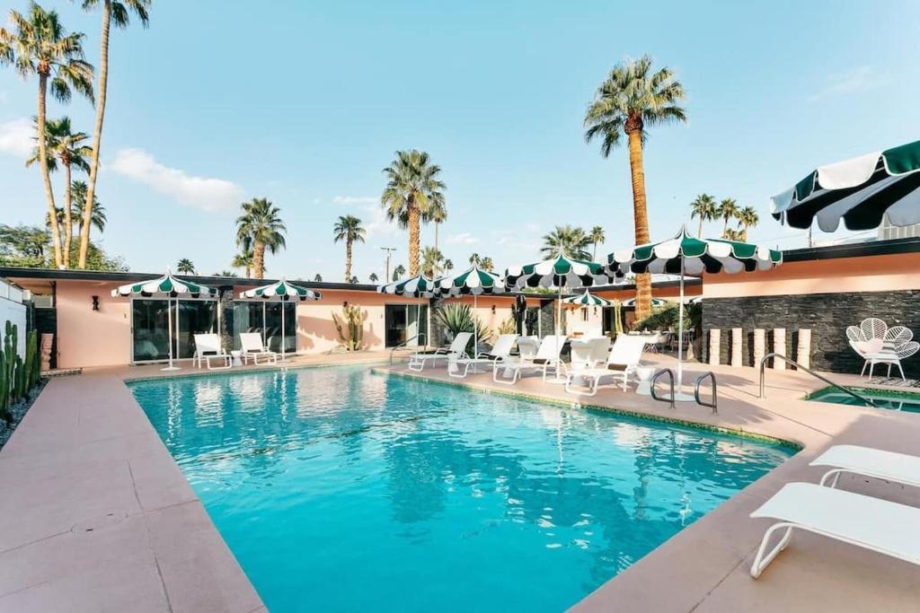 uma piscina com cadeiras e guarda-sóis em um resort em The Marley by AvantStay Mid-Century Modern Retreat with Pool & Mountain Views em Palm Springs