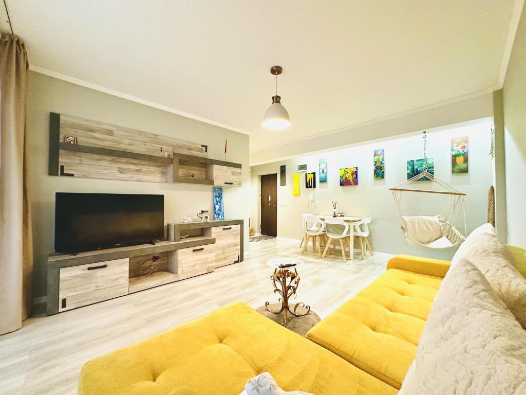 a living room with a yellow couch and a television at Apartament elegant - Cozy home residence in Piteşti