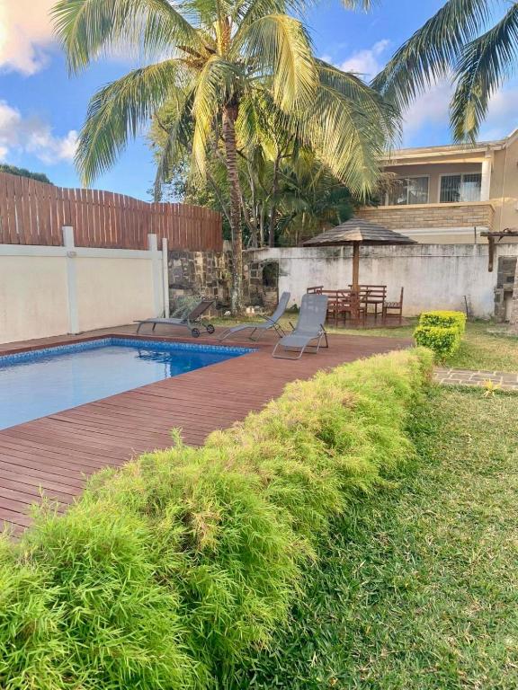 a backyard with a wooden deck and a swimming pool at Villa Chanel avec piscine proche de la plage in Grand-Baie