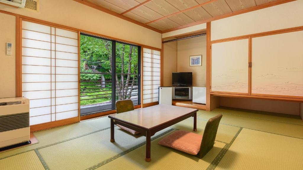a living room with a table and chairs and windows at Hayataro Onsen Komagane Kogen Retreat Suzuran Haya - Vacation STAY 34218v in Komagane