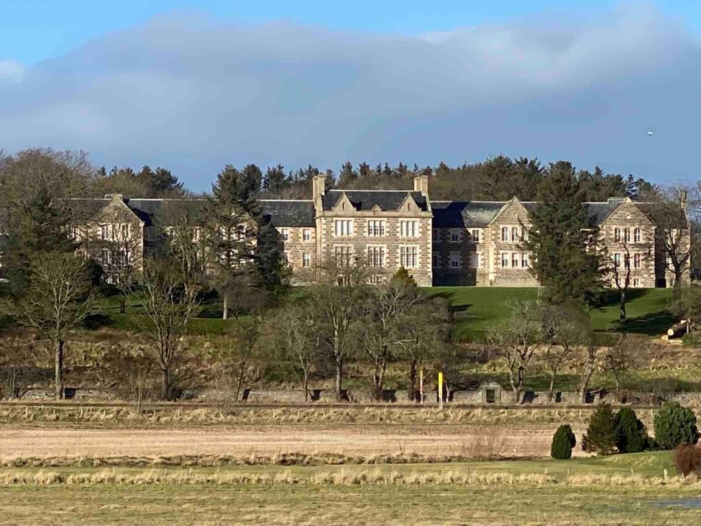 una grande casa su una collina con alberi e un campo di 2 bedroom Townhouse within Grade C listed Ladysbridge House a Ladysbridge Station