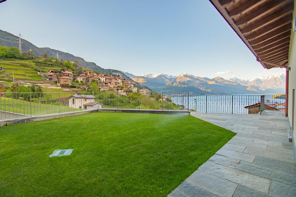 a patio with a green lawn with mountains in the background at VILLA SANT'ANNA - ALBA by Curtiaffitti in Pianello Del Lario