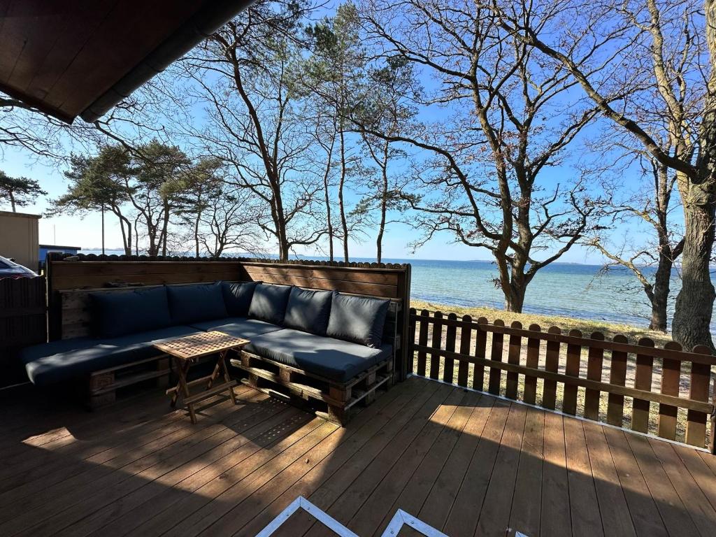 un sofá sentado en una terraza junto al agua en Surf-Bungalow in erster Reihe, en Klein Strömkendorf