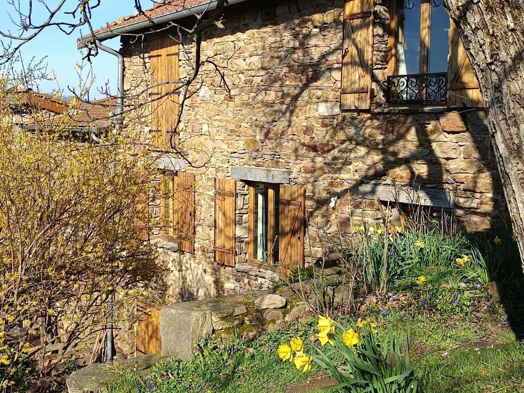 an old stone building with a balcony and flowers at Les jardins de Montaland in Sainte-Catherine-sur-Riverie