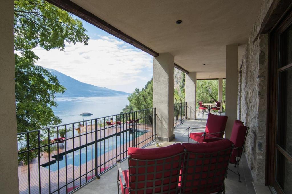 a balcony with red chairs and a view of the water at Casa Sopino 2 in Limone sul Garda