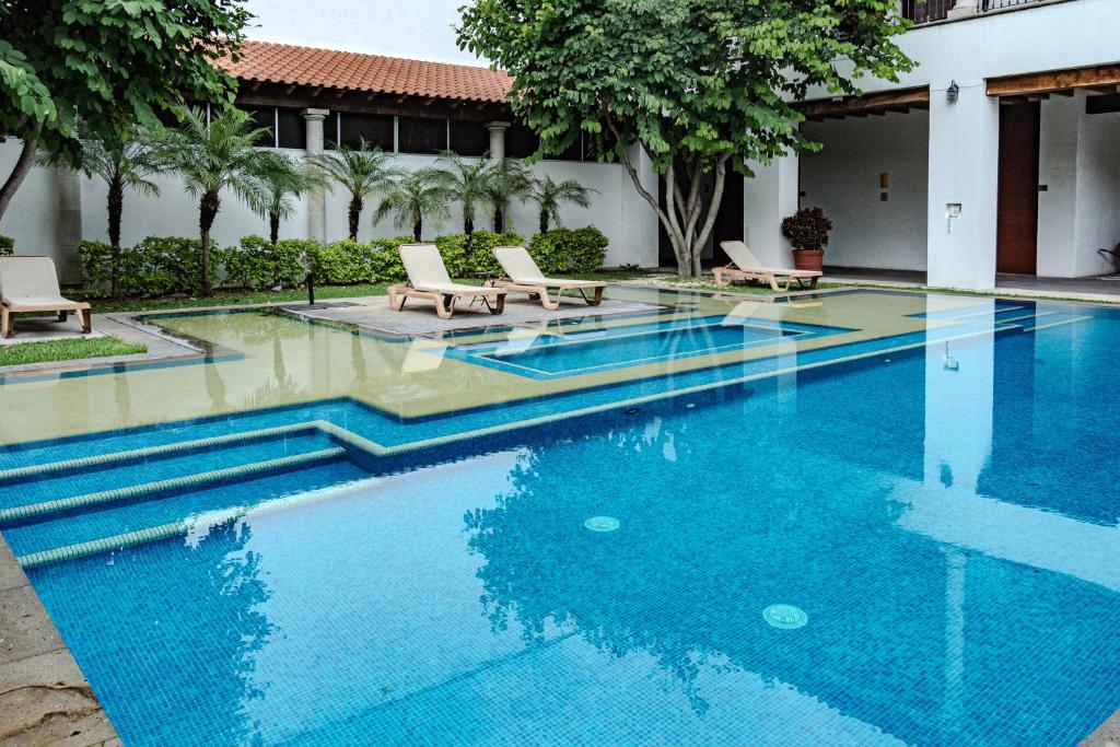 a swimming pool at a resort with chairs and trees at Radisson Hotel Cuernavaca in Chiconcuac