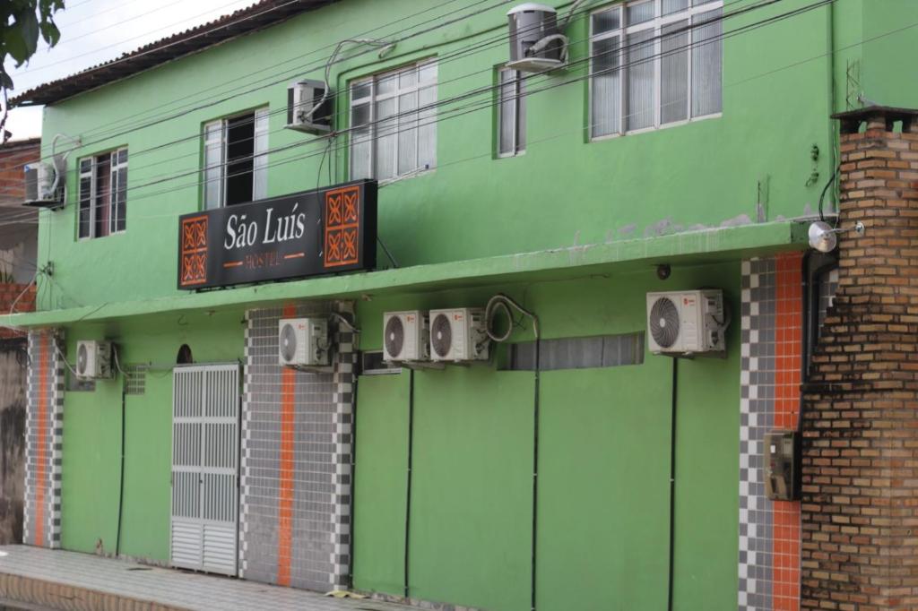 um edifício verde com um sinal em São luís Hostel em São Luís
