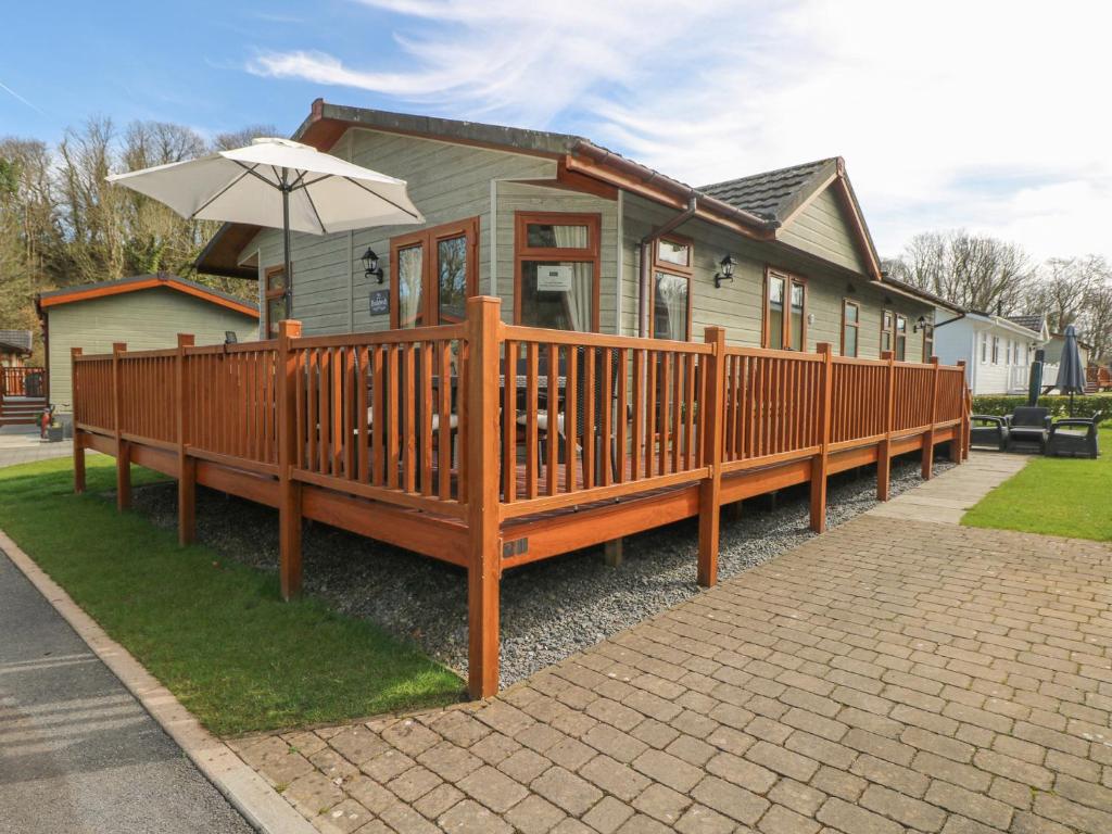 a house with a wooden deck with an umbrella at Heddwch in Stepaside