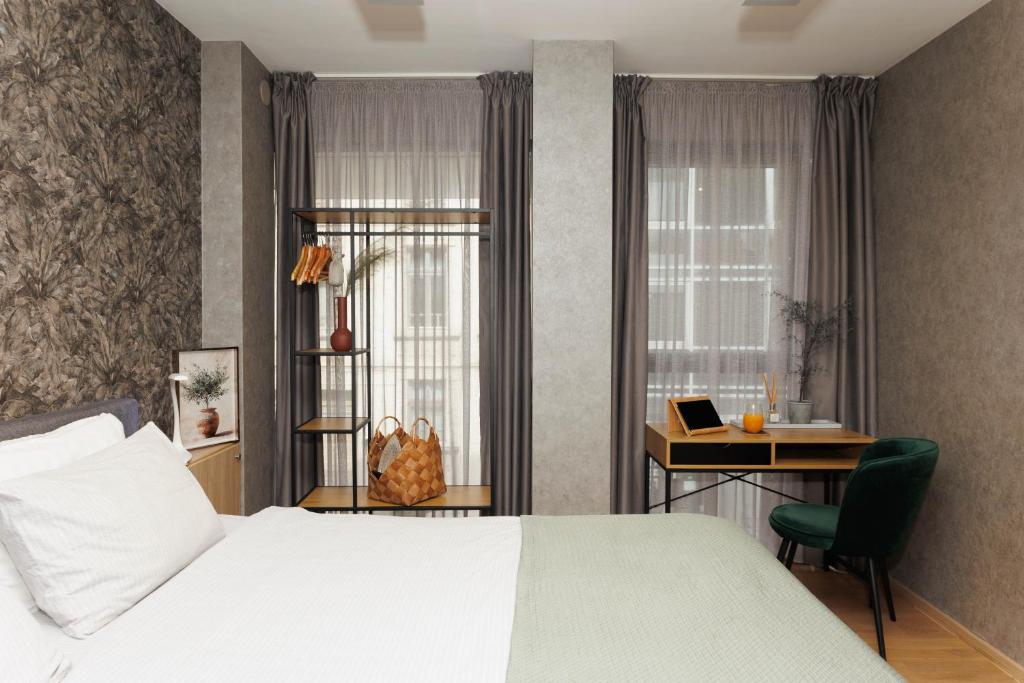 a bedroom with a bed and a desk and a window at City Center Apartments with Parking in Plovdiv