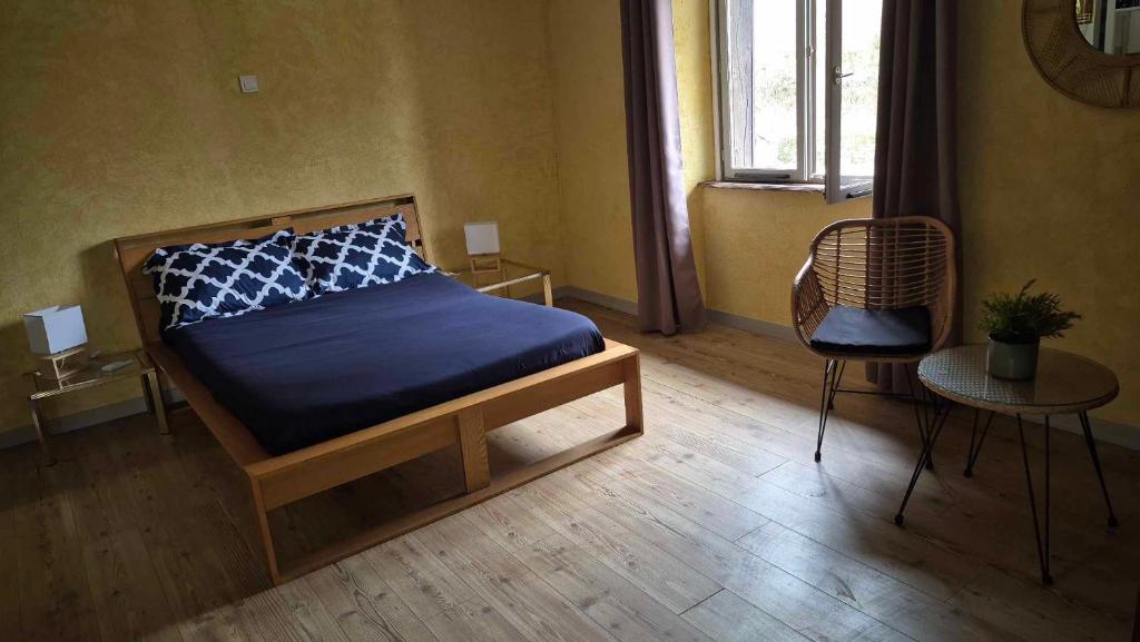 a bedroom with a bed and a chair and a window at Nature en petite montagne in Arinthod