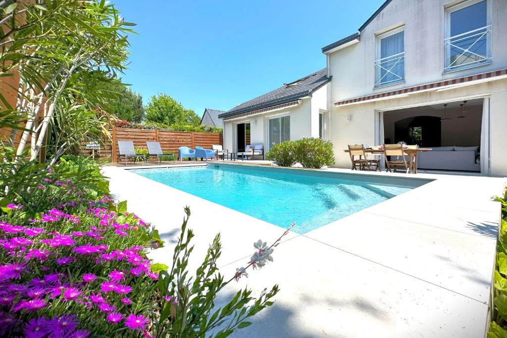 - une piscine dans l'arrière-cour d'une maison ornée de fleurs violettes dans l'établissement La Céleste-Villa standing avec piscine et jardin, à Saint-Herblain