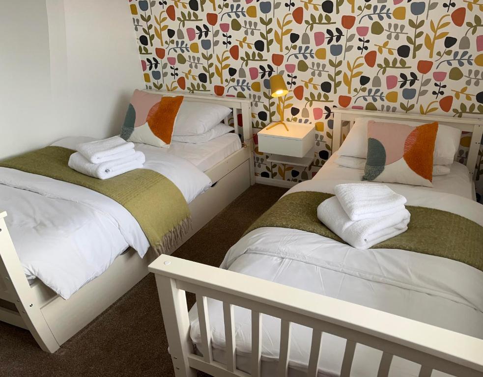 two beds in a small room with a wallpaper at High Trees in Chichester
