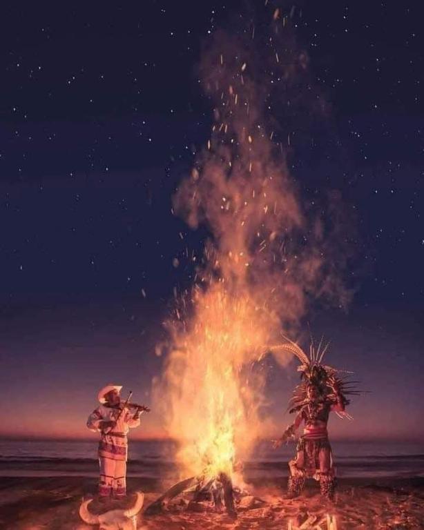 two people standing around a fire on the beach at Casas in Monterrey