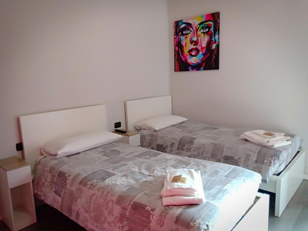 two beds in a room with a painting on the wall at Le Stanze di Marco in Monza