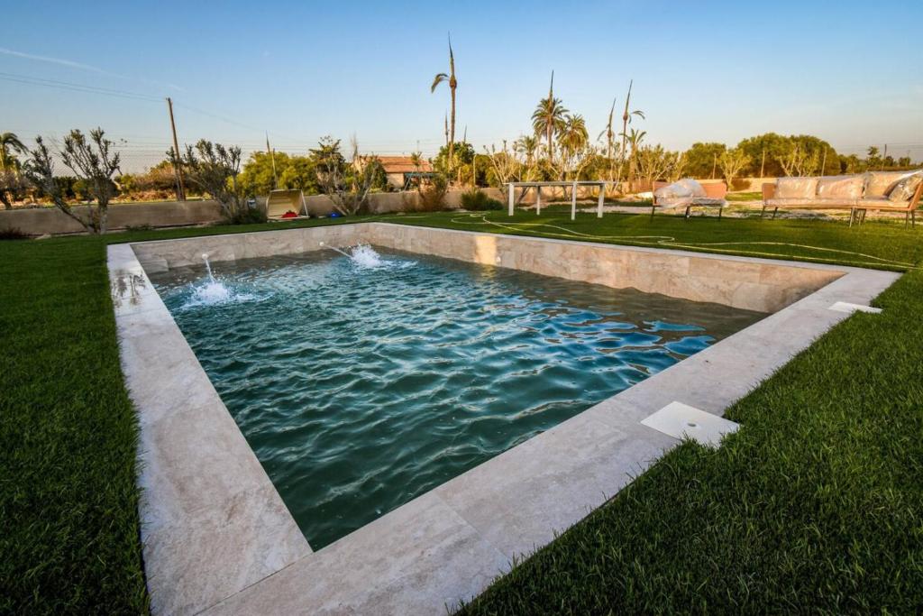 a swimming pool in the middle of a grass field at Sweetstaybykw Moderna Casa Campo con Piscina in Asprillas