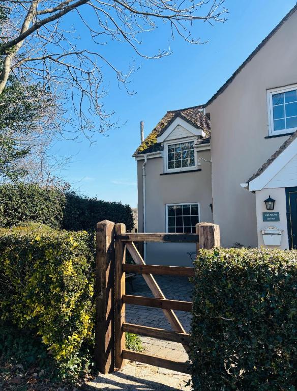 a wooden gate in front of a white house at Dolmans Retreat in Lytchett Matravers