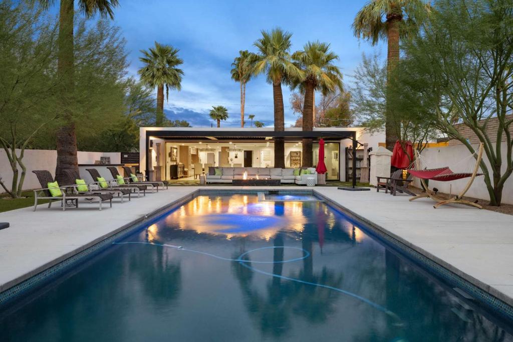 a pool with chairs and a house with palm trees at Arcadia Beach Club - 4-Villa Luxe Retreat with Pool in Phoenix